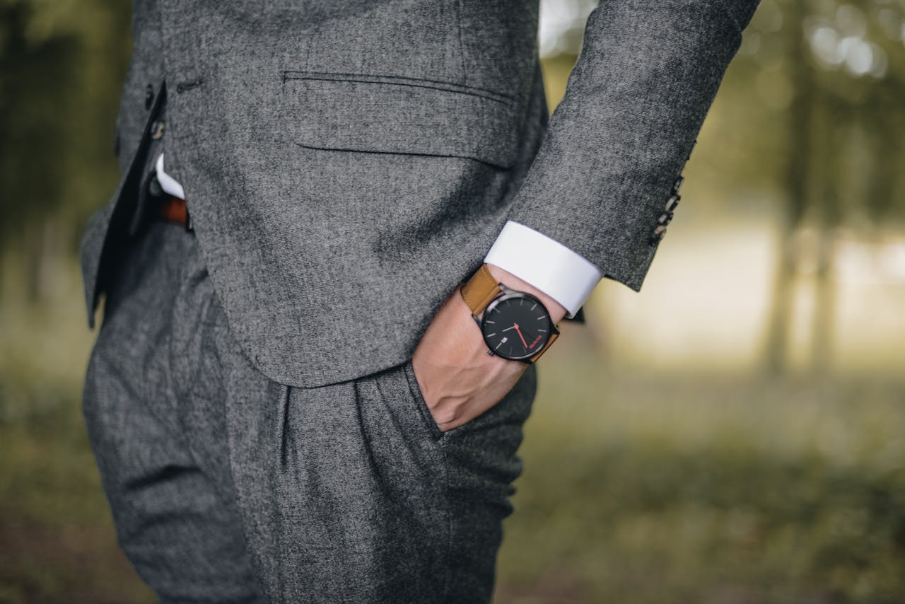 about-us Close-up of a man in a tailored suit wearing an elegant wristwatch outdoors, exuding fashion and sophistication.